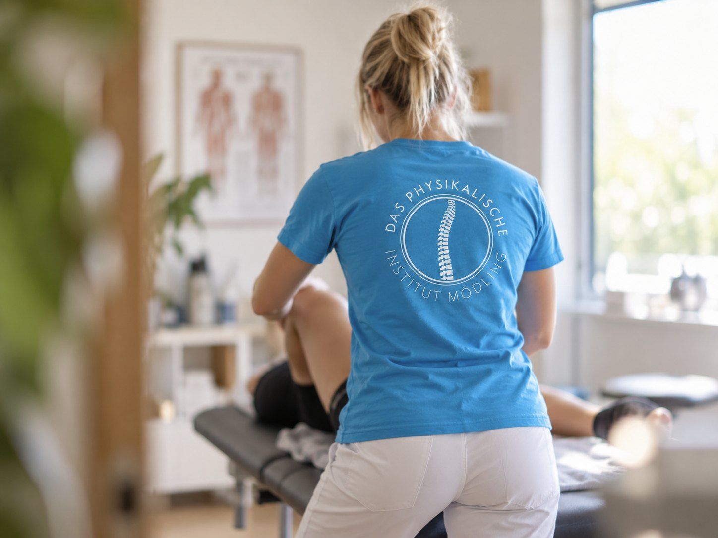Therapeutin im hellblauen T-Shirt mit Praxislogo am Rücken